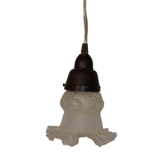 En retro 60'er loftlampe med en riflet, hvid glasskærm med en bølget kant og et dekorativt reliefmønster øverst, monteret i en mørkebrun bakelitfatning.